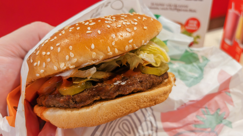 Burger King Whopper close up in someone's hand with paper wrapping