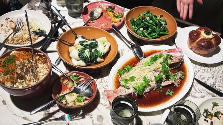 A flat lay of various dishes from Mr. Jiu's with cutlery casually scattered on top.