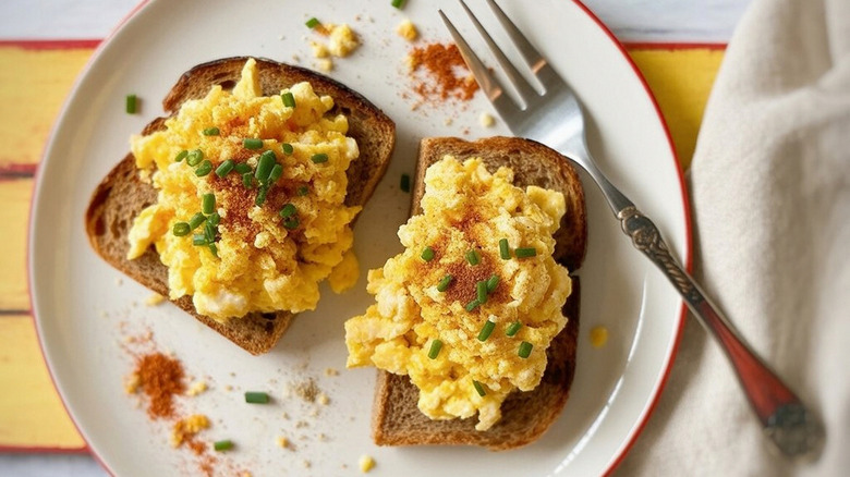 Scrambled eggs on toast, garnished with spice and fresh herbs