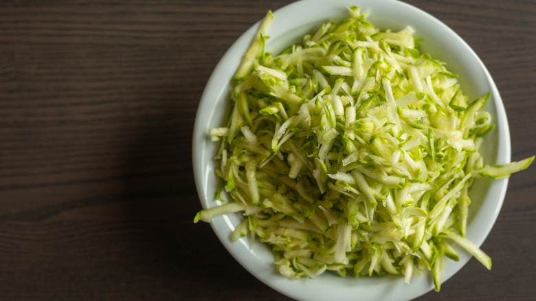 A white bowl of shredded zucchini