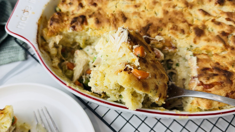 Spooning cheesy chicken cobbler out of baking dish