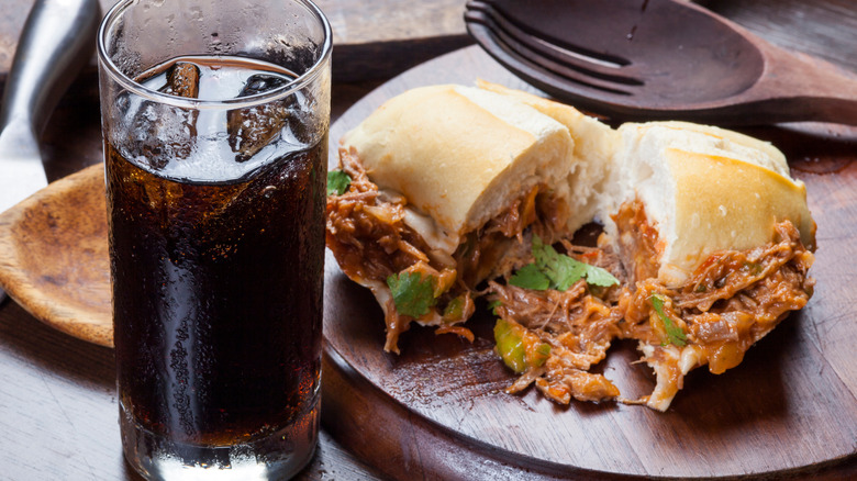 soda and a sandwich with shredded meat