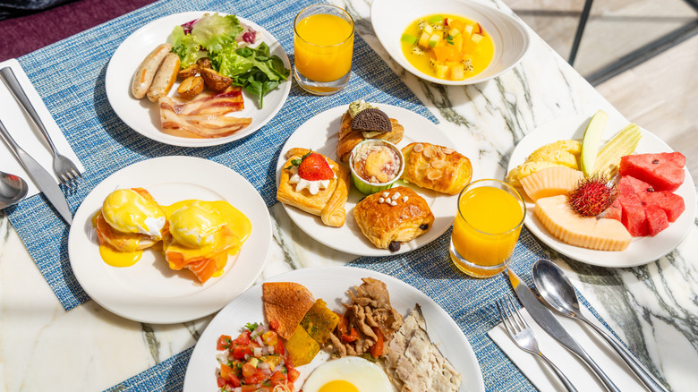 a variety of breakfast foods on a table, including bacon, sausage, and pastries
