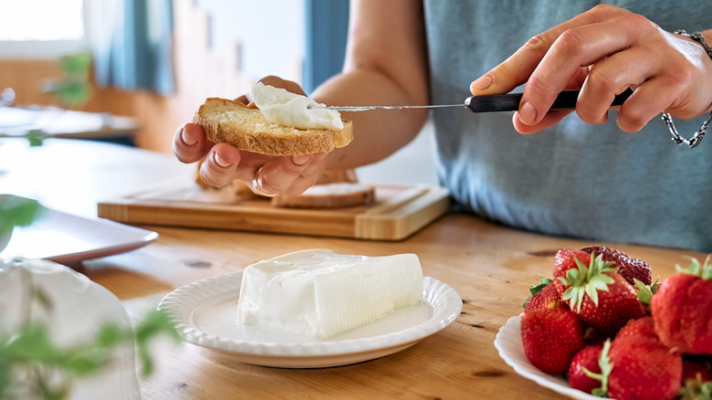 woman spreading cream cheese on toast
