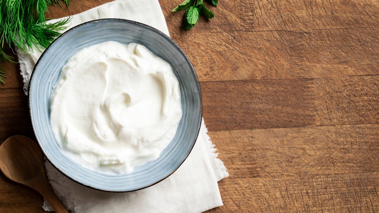Sour cream in blue bowl on wood table