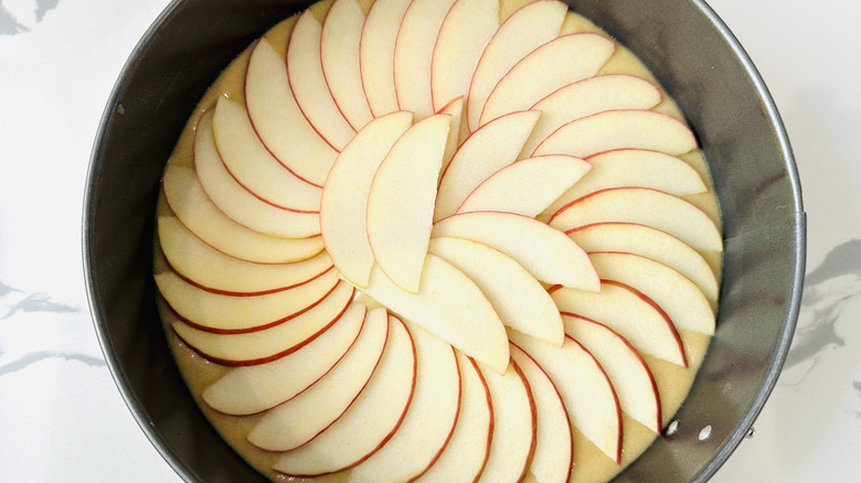Sliced apples over cake batter in pan