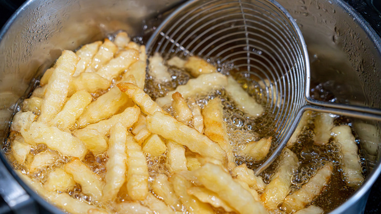 Close up of french fries frying in a pot of oil