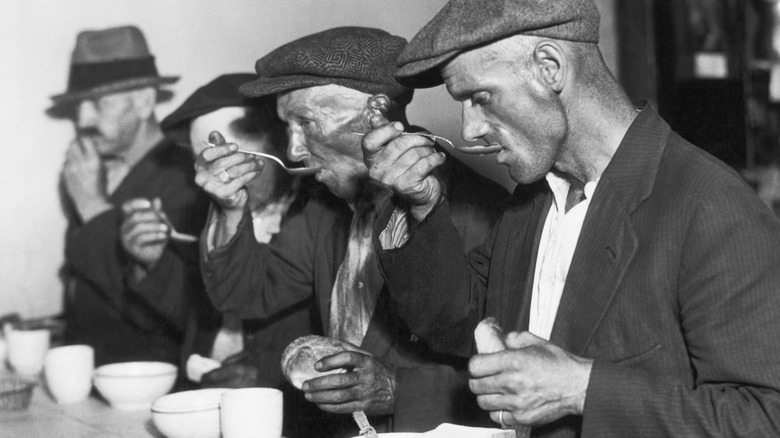 Black-and-white photograph of men eating food during the Great Depression