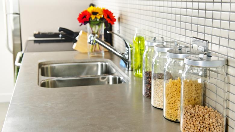 Natural stone countertop with jarred dry storage next to stainless steel sink.