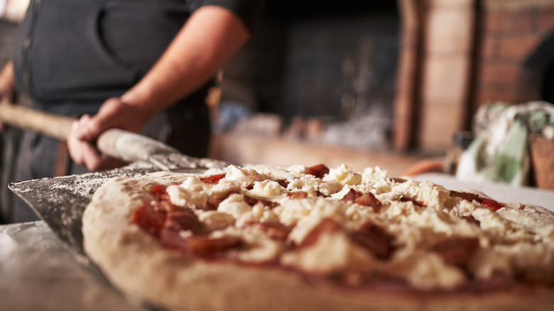 chef placing pizza in oven