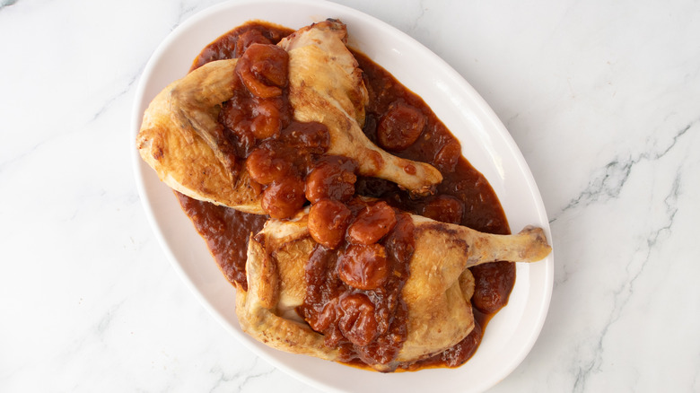 chicken in reddish-brown liquid on a white plate