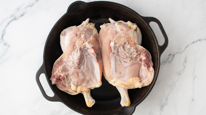 raw chicken in a black frying pan