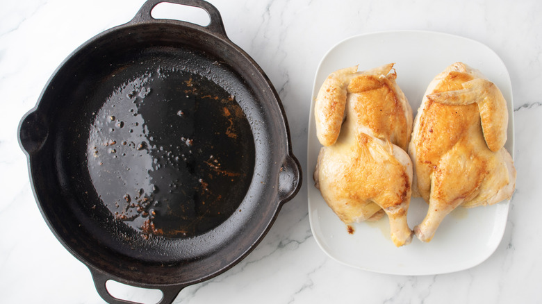browned chicken next to a black frying pan