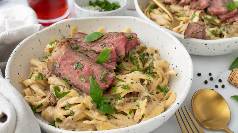 noodles with steak and herbs in a white bowl