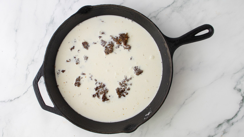 chopped vegetables and milk in a black frying pan
