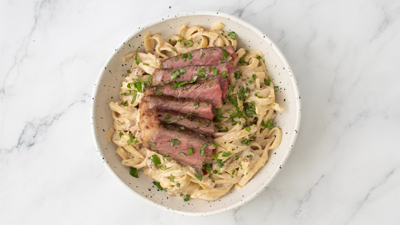 noodles with steak and herbs in a white bowl