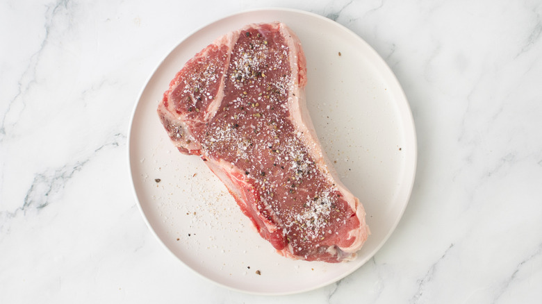 salted raw steak on a white plate