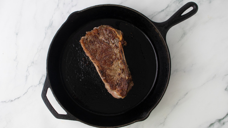 steak in a black frying pan