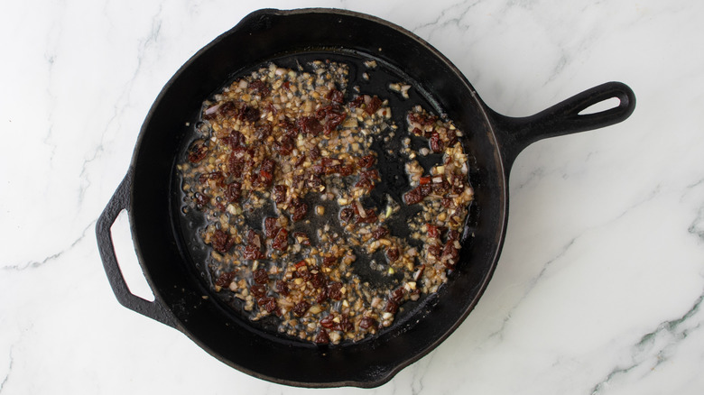 chopped vegetables and liquid in a black frying pan