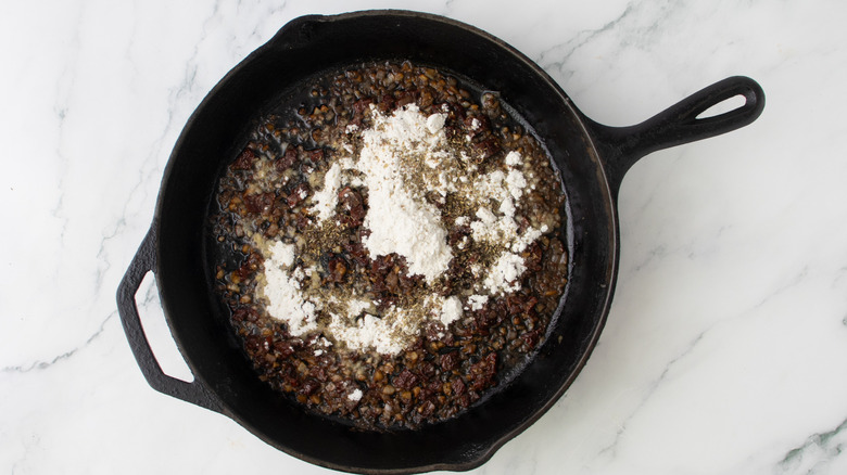 chopped vegetables and flour in a black frying pan