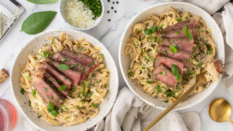 noodles with steak and herbs in white bowls