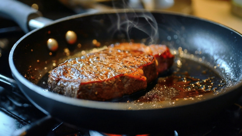steak being seared in a pan