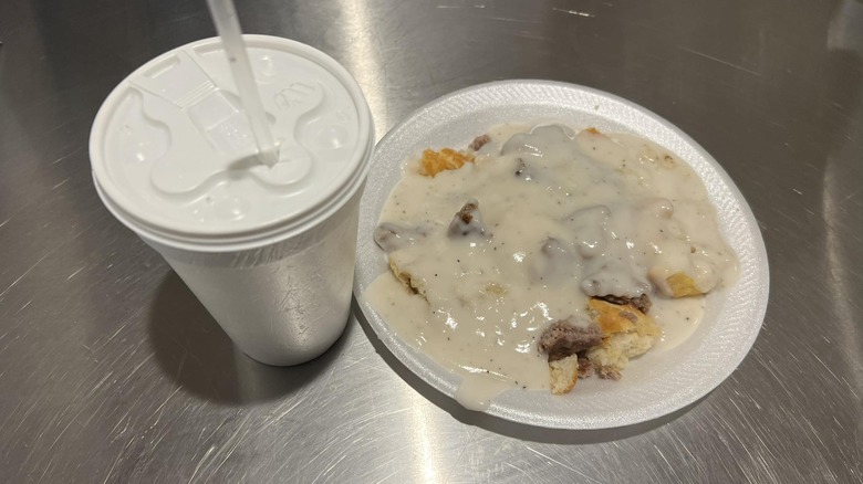 Biscuits and gravy on a plate next to a small drink