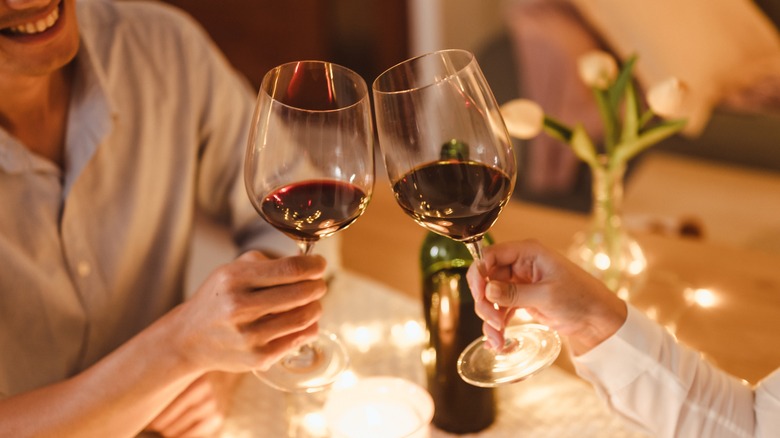 two people toasting with glasses of red wine
