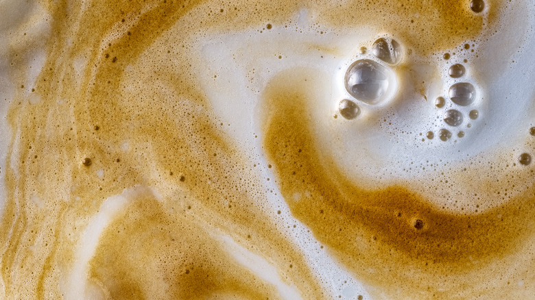 close-up of coffee swirling with milk