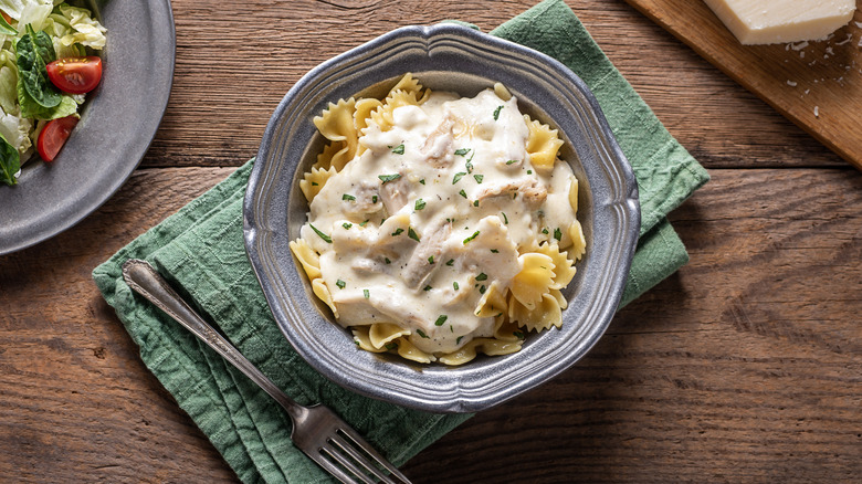 a bowl of chicken alfredo over bowtie pasta
