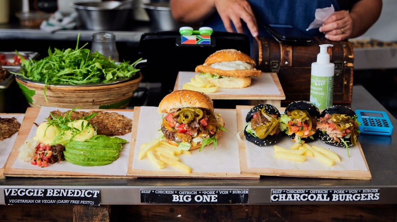 Person preparing burgers on a board