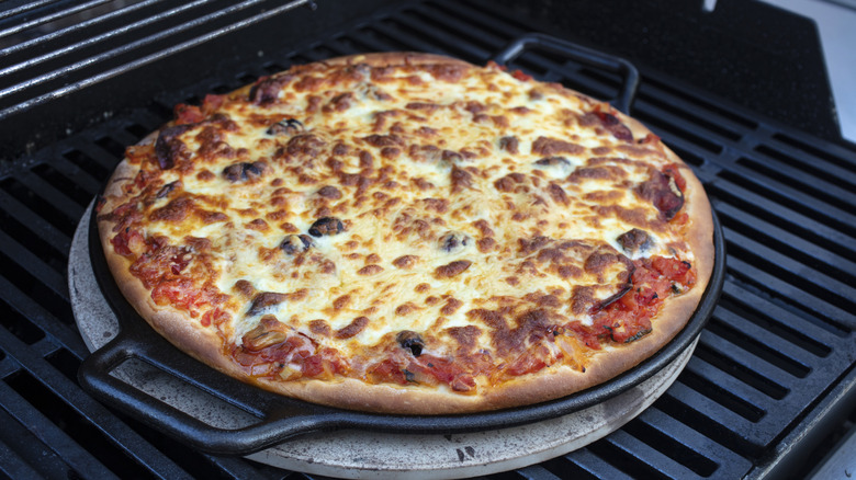 Steel pizza pan on grill with freshly made pizza