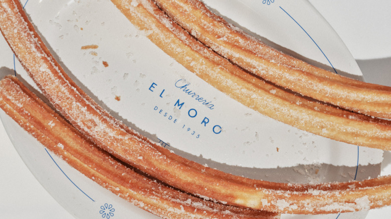 Four churros on a plate with the El Moro logo