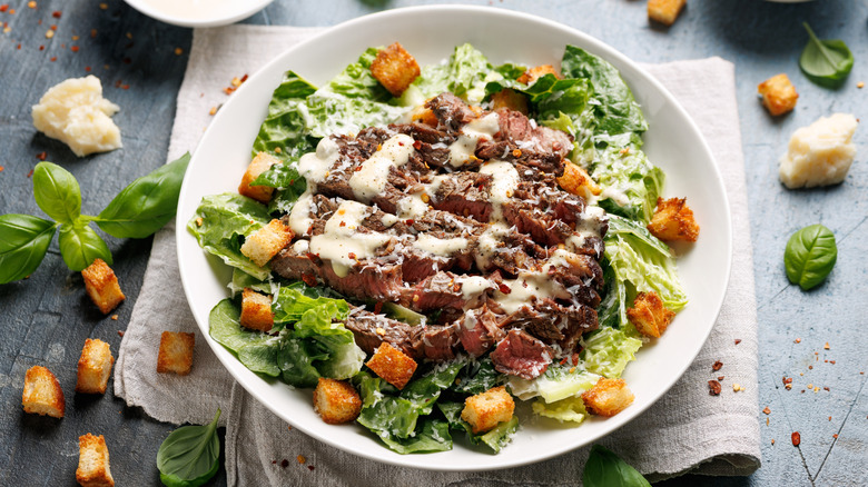 Caesar salad topped with steak