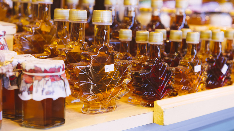 Decorative bottles of maple syrup lined up on a shop shelf.