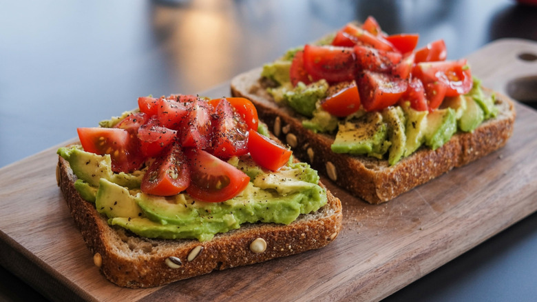 avocado toast with tomatoes on a cutting board