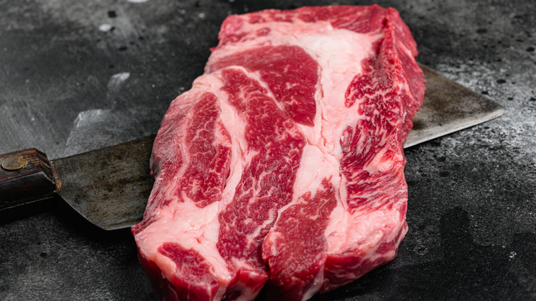 A cut of chuck steak on a dark stone table.