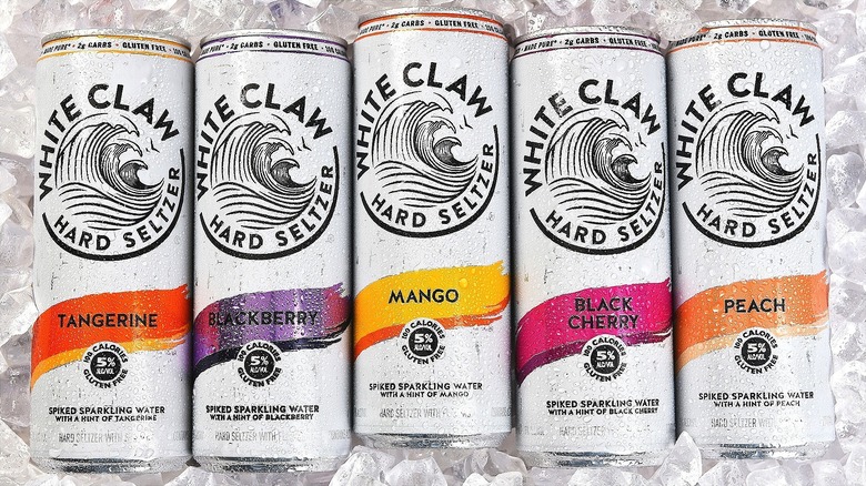 Five White Claw seltzers in various flavors over ice