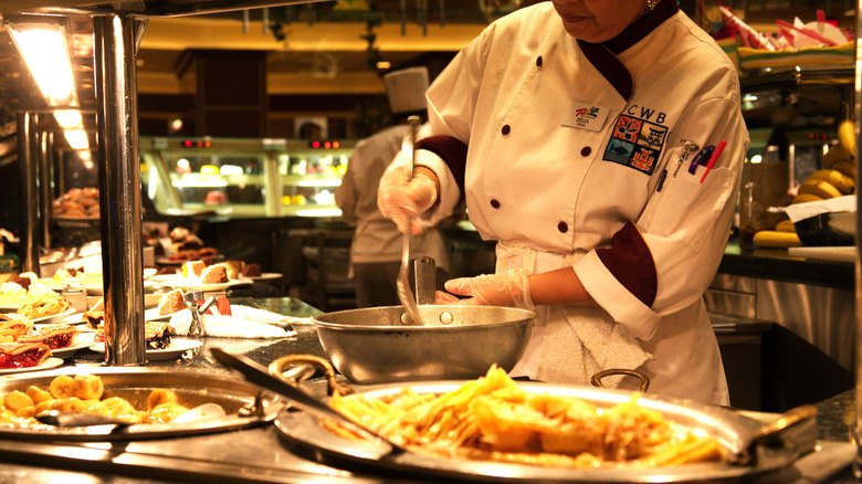 A casino worker stirs a metal spoon in a metal bowl behind a buffet in Las Vegas
