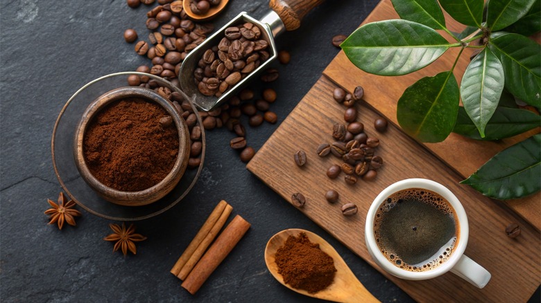 Brewed coffee on table beside espresso, spices, and beans
