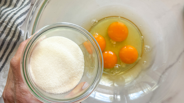 hand adding monk fruit to bowl with eggs