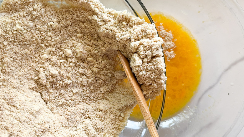 Dry baking mixture going into bowl with egg mixture