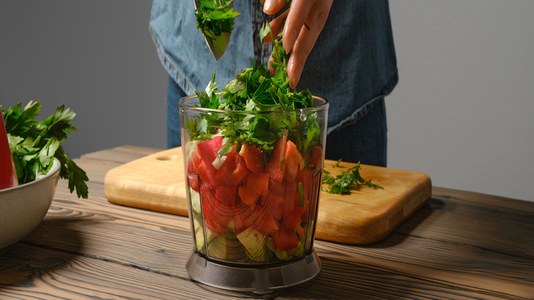 Person putting salsa ingredients into food processor