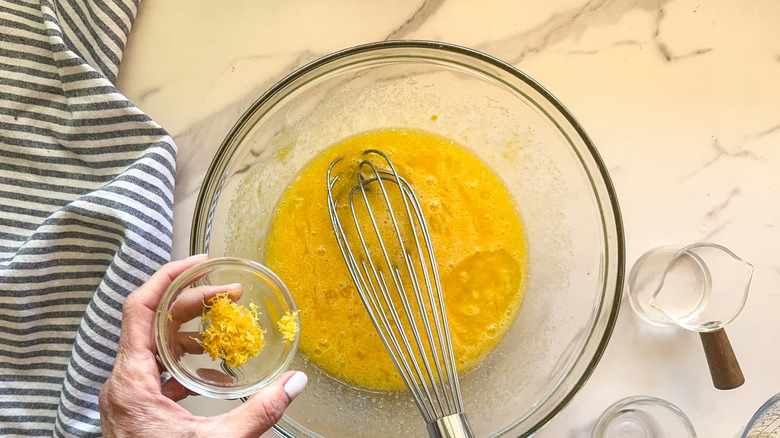 hand adding lemon zest to bowl