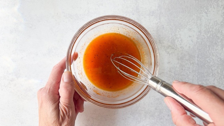 Whisking chicken marinade in small glass bowl