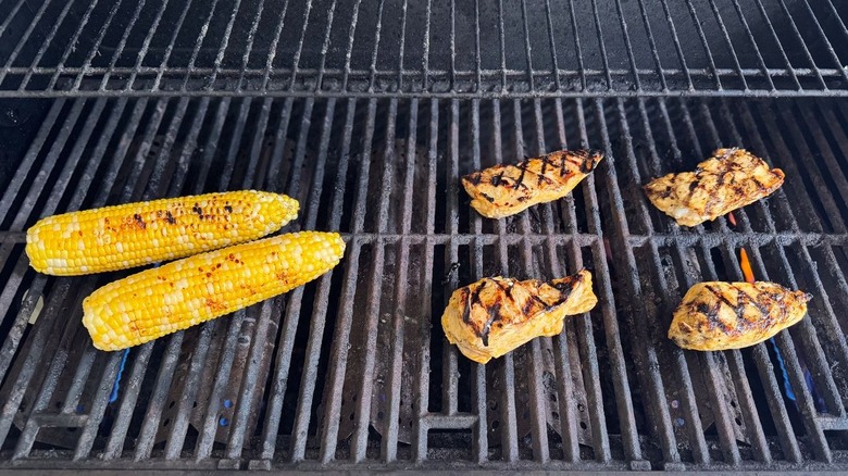 Corn on the cob and chicken breasts on grill