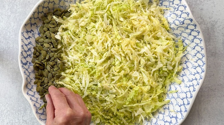 Raw pepitas and shredded cabbage in bowl
