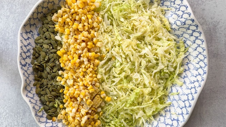 Pepitas, grilled corn, and shredded cabbage in serving bowl