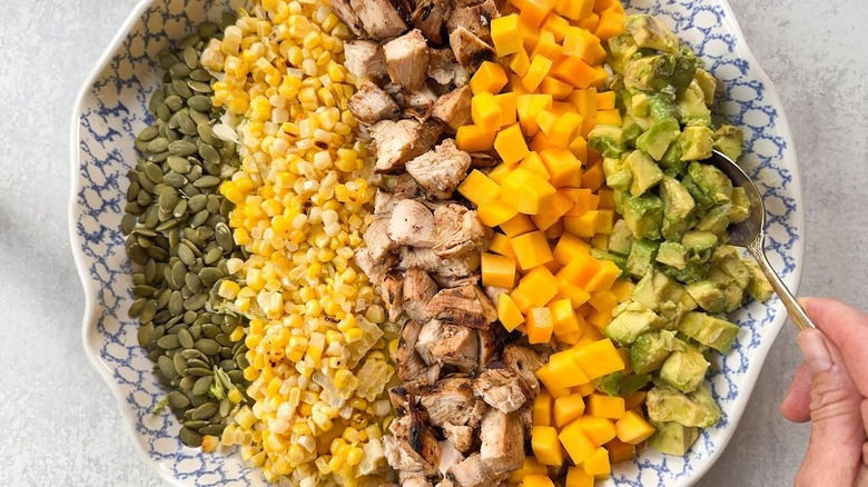 Adding diced avocado to chopped salad