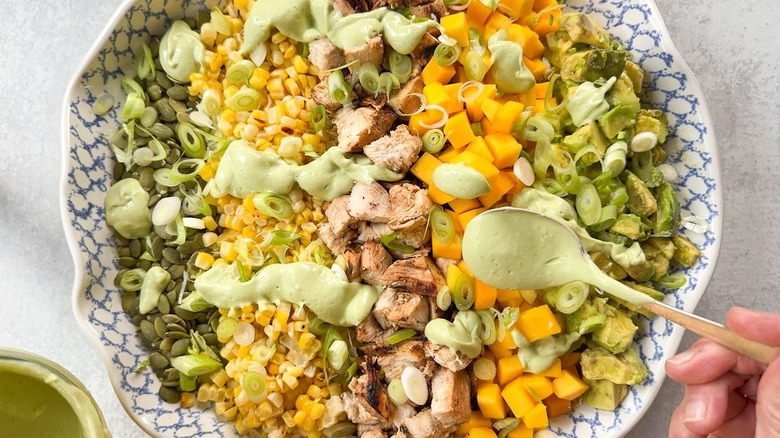 Adding avocado ranch dressing to chopped salad